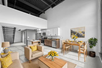 A modern living room with a dining area and a kitchen in the background.